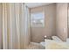 Cozy bathroom includes a patterned shower curtain, window with blinds, and a standard toilet at 11834 Planters Estates Dr, Charlotte, NC 28278