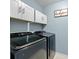 Modern laundry room with a front-loading washer and dryer, white cabinets, and a decorative sign at 11834 Planters Estates Dr, Charlotte, NC 28278