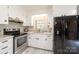 Well-lit kitchen featuring stainless steel appliances, granite countertops, white cabinets, and a modern black refrigerator at 1211 25Th Se St, Hickory, NC 28602