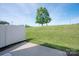 A serene backyard view showcasing lush green grass, a solitary tree and a concrete patio at 1498 Burrell Nw Ave, Concord, NC 28027