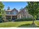 Beautiful two-story brick home with a manicured lawn, stone accents, covered porch, and mature trees at 16547 Bastille Dr, Charlotte, NC 28278