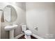 This powder room features a pedestal sink, round mirror, and wood look flooring at 16547 Bastille Dr, Charlotte, NC 28278