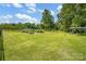 Large backyard featuring lush green grass, mature trees, and a covered parking area at 169 Primrose Ln, Statesville, NC 28625