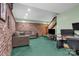 Spacious finished basement with green carpet, exposed brick, comfortable sofa and a workstation at 169 Primrose Ln, Statesville, NC 28625