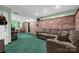 Finished basement with green carpet, brick accent wall, and a comfortable sofa with patterned pillows at 169 Primrose Ln, Statesville, NC 28625