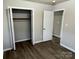 A view of the primary bedroom with an open closet featuring hardwood floors and neutral colors at 1714 Maribel Ave, Charlotte, NC 28216