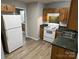 Kitchen features wood cabinets, white appliances, and green countertops with view into adjacent room at 1714 Maribel Ave, Charlotte, NC 28216