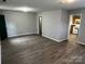 Inviting living room with dark-wood floors, neutral walls, and access to kitchen with white appliances at 1714 Maribel Ave, Charlotte, NC 28216