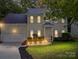 Inviting two-story home with landscape lighting enhancing its charming facade and well-maintained front yard at dusk at 216 Devon Forest Dr, Mooresville, NC 28115