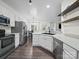 Open-concept kitchen with stainless steel appliances, white cabinets, and modern fixtures, seamlessly connecting to dining area at 216 Devon Forest Dr, Mooresville, NC 28115