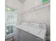 A functional laundry room boasts modern washer and dryer units and ample shelving for storage at 216 Devon Forest Dr, Mooresville, NC 28115