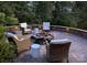 Outdoor stone patio with seating around a fire pit, surrounded by mature trees at 369 Skyland Ct, Mount Gilead, NC 27306