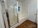 Bright bathroom featuring a glass-enclosed shower and soaking tub, complemented by wood-look flooring at 40287 Palmerville Rd, New London, NC 28127