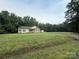 Expansive lawn surrounds a well-kept single-story home nestled among mature trees providing a private setting at 40287 Palmerville Rd, New London, NC 28127