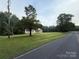 A long, green lawn surrounds a cozy, single-story home, with a road in the foreground and forest in the background at 40287 Palmerville Rd, New London, NC 28127