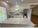 Bright kitchen featuring white cabinets, marble countertops, a stainless steel refrigerator, and a view of the backyard at 40287 Palmerville Rd, New London, NC 28127