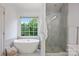Modern bathroom featuring a soaking tub, a walk-in shower, and a large window at 5005 Chestnut Knoll Ln, Charlotte, NC 28269