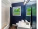 Bathroom featuring modern vanity, neutral tile, dark blue paint, bright window, and shower with blue curtain at 7016 Tirzah Rd, Waxhaw, NC 28173