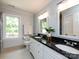 Bright bathroom with a double sink vanity, black granite countertop, and a large window offering natural light at 9415 Braemar Ter, Charlotte, NC 28210
