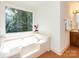Bright bathroom features a garden tub under a large window overlooking the greenery at 9415 Braemar Ter, Charlotte, NC 28210