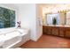 Well-lit bathroom featuring a garden tub under a large window and double sink vanity at 9415 Braemar Ter, Charlotte, NC 28210