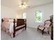 Bedroom with wooden bed frame, floral chair, two windows, and soft, natural light at 9415 Braemar Ter, Charlotte, NC 28210