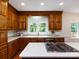 Bright kitchen features wood cabinetry, a center island cooktop, and a view to the backyard at 9415 Braemar Ter, Charlotte, NC 28210