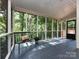 Cozy screened porch with tile flooring, a bench with pillow, and views of the wooded backyard at 9415 Braemar Ter, Charlotte, NC 28210