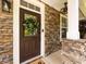 Inviting front door with decorative wreath and stone accents create a warm and welcoming entry at 12928 Windy Lea Ln, Huntersville, NC 28078