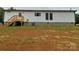 Exterior side view of the home showcasing white siding, a wooden staircase, and unfinished yard at 130 Zircon Dr, Statesville, NC 28625