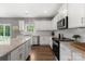 Bright kitchen with granite countertops, stainless steel appliances, white cabinetry, and hardwood floors at 132 Sycamore Crossing Ct, Locust, NC 28097