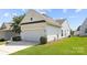 View of the home's garage with a dark accent above and a lovely landscaped lawn space at 1471 River Bend Blvd, Indian Land, SC 29707