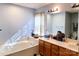 Bright bathroom featuring a soaking tub, wood vanity with white countertop, and large mirror at 1902 Stonewyck Ave, Kannapolis, NC 28081