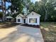 Inviting single-story home featuring white siding, black shutters, and a new concrete driveway at 219 Pine St, Rockwell, NC 28138