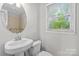 Traditional bathroom featuring a pedestal sink, toilet, large window, and vanity at 2800 Georgia Ave, Charlotte, NC 28205