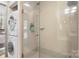 Tiled shower with glass doors and stacked washer and dryer in bathroom at 297 Mcdonald Ave, Charlotte, NC 28203