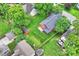 An aerial view of a red house with a fenced in yard, shed, green lawn, and beautiful surrounding trees at 3519 Card St, Charlotte, NC 28205