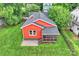 Aerial view showcasing the red home with its gray roof, screen porch, and verdant surrounding landscape at 3519 Card St, Charlotte, NC 28205