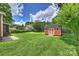 Spacious backyard with lush green grass and a cute red storage shed with white trim at 3519 Card St, Charlotte, NC 28205