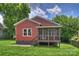 Backyard view of home with a red exterior, green grass, and a screened in porch at 3519 Card St, Charlotte, NC 28205