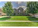 Brick two-story home with manicured lawn, lush trees and shrubbery under a blue sky with puffy white clouds at 3913 Widgeon Way, Waxhaw, NC 28173