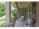 Comfortable front porch seating area with brick posts, two chairs with cushions, and small tables at 3913 Widgeon Way, Waxhaw, NC 28173