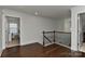 Hallway featuring hardwood floors and iron rod railing with open doorways on either side at 3913 Widgeon Way, Waxhaw, NC 28173