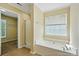 Bright bathroom with soaking tub, tiled floor and shower, and view into closet at 4982 Bentgrass Run Dr, Charlotte, NC 28269