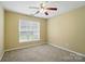 Cozy bedroom featuring neutral paint, carpet, ceiling fan, and a window letting in natural light at 4982 Bentgrass Run Dr, Charlotte, NC 28269