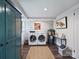 Bright laundry room featuring modern appliances, an aqua cabinet, and wood-look flooring at 5436 Topping Pl, Charlotte, NC 28209