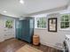 Well-lit laundry room with a teal cabinet, two windows with exterior view, and wood-look floors at 5436 Topping Pl, Charlotte, NC 28209