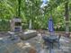 Outdoor patio featuring a brick fireplace, cozy seating, and stone flooring, surrounded by lush greenery at 5436 Topping Pl, Charlotte, NC 28209