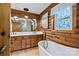 Bathroom featuring wood walls, white cabinets, double vanity, tub, and picture window at 6836 Summer Hill Dr, Denver, NC 28037