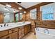 Bathroom featuring wood walls, white cabinets, double vanity, tub, and picture window at 6836 Summer Hill Dr, Denver, NC 28037